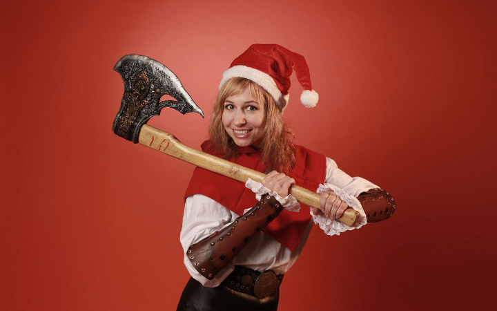 Victoria dressed as a Christmas elf holding a giant axe and flashing a mischievous grin