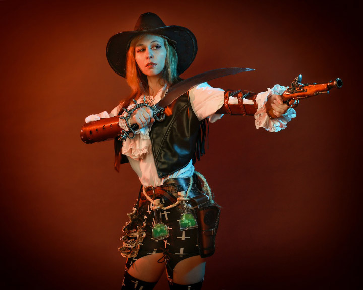 Victoria in Van Helsing cosplay with cross-patterned garters, a knife, and a gun.