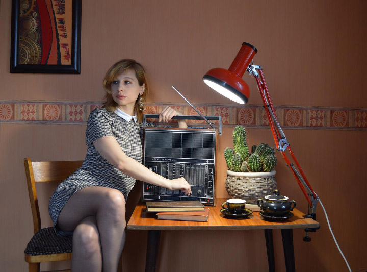 Victoria tuning an old radio in a retro plaid dress