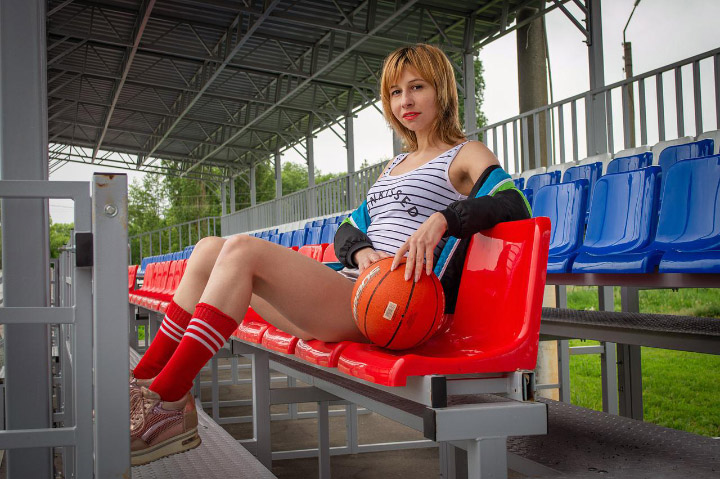 Victoria wearing sporty clothes and  sitting in the bleachers of a small sports field.